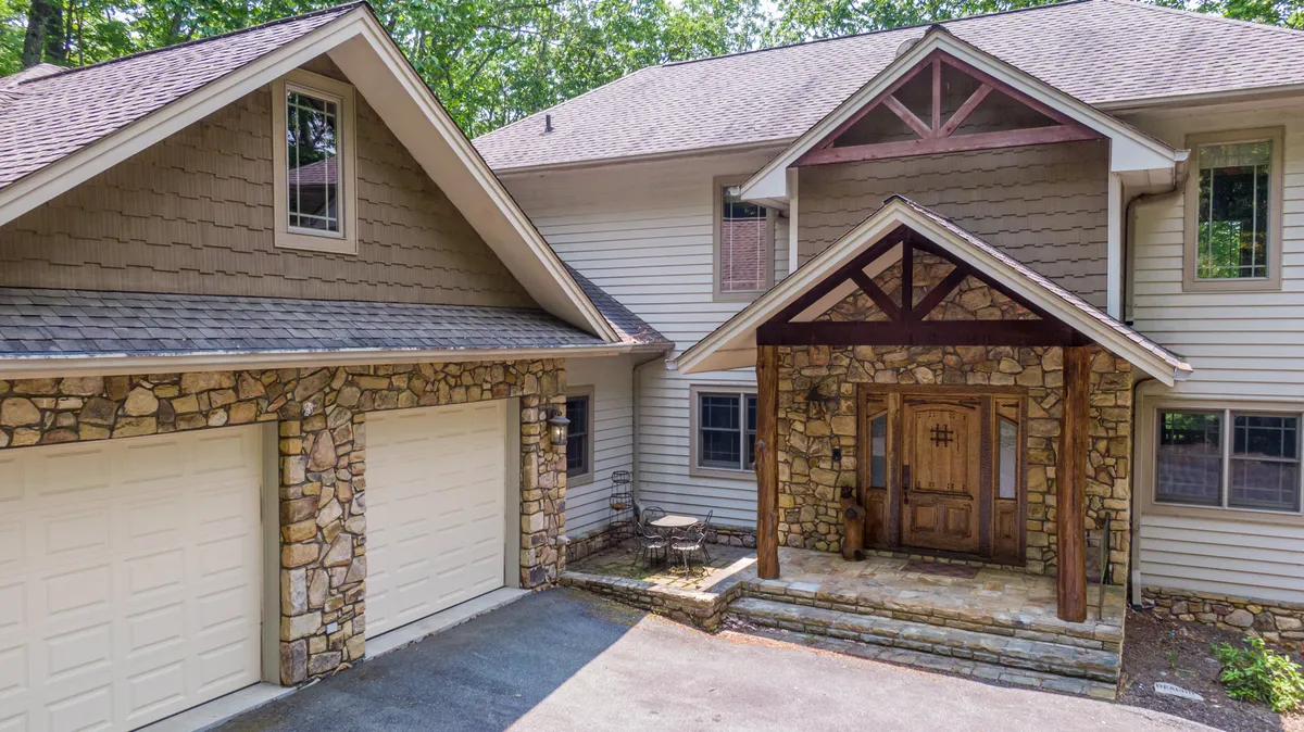 This exterior shot presents the welcoming front porch of Amitola, featuring a stone facade, wooden door, gabled roof, and inviting outdoor seating. The lush greenery and quiet setting emphasize a sense of arrival and serenity, perfectly setting the stage for a family retreat at the heart of the High Country.